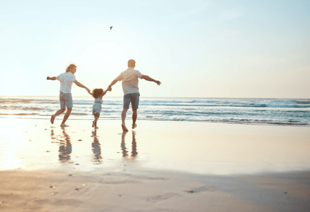 Dads on beach with daughter representing a family built through egg donation.